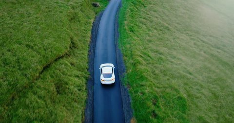 Cinematic aerial view of electric car driving on country road at sunset 스톡 비디오