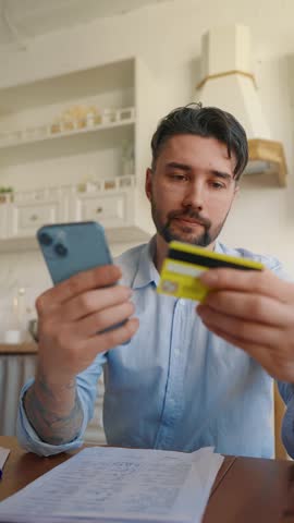 Man online paying credit card on phone. Concentrated man paying mobile phone money finances shopping ecommerce enter secure code safe transaction at home, planning a trip. Online paying concept.
