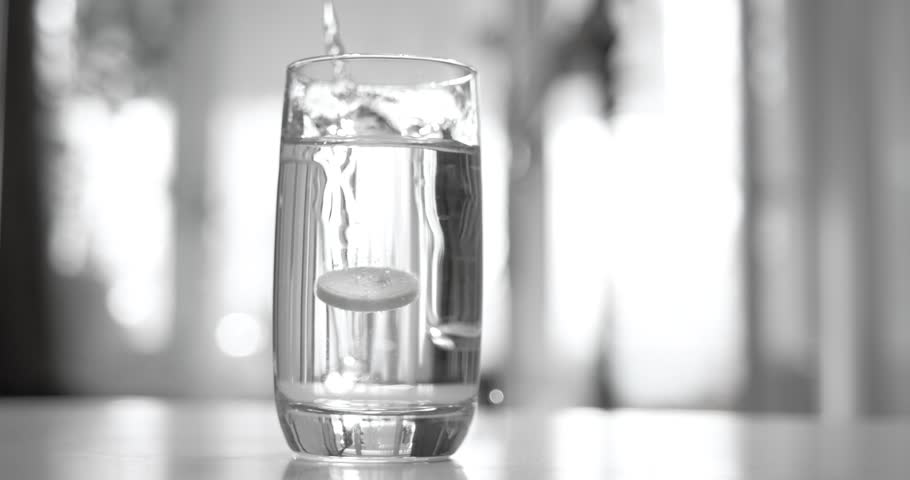 Effervescent aspirin pill in a glass of wate. Soluble tablet shot on super slow motion camera 1000 fps.