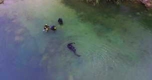 aerial. Divers enter a huge underwater cave at the bottom of a granite quarry. Divers are immersed in water on a small lake. Summer cloudy day. Lanshaft of the lake. 