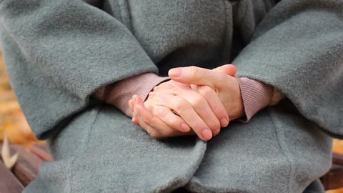 Elder ill woman outside in park in psychiatric hospital, rubbing hands nervously