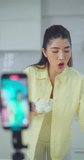 Focused woman uses her smartphone for a video call in a bright, blurred kitchen setting.	