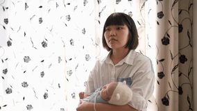 Slow-motion video of a Taiwanese mother in her 20s chanting a 1-month-old girl's baby in front of the curtain in the room