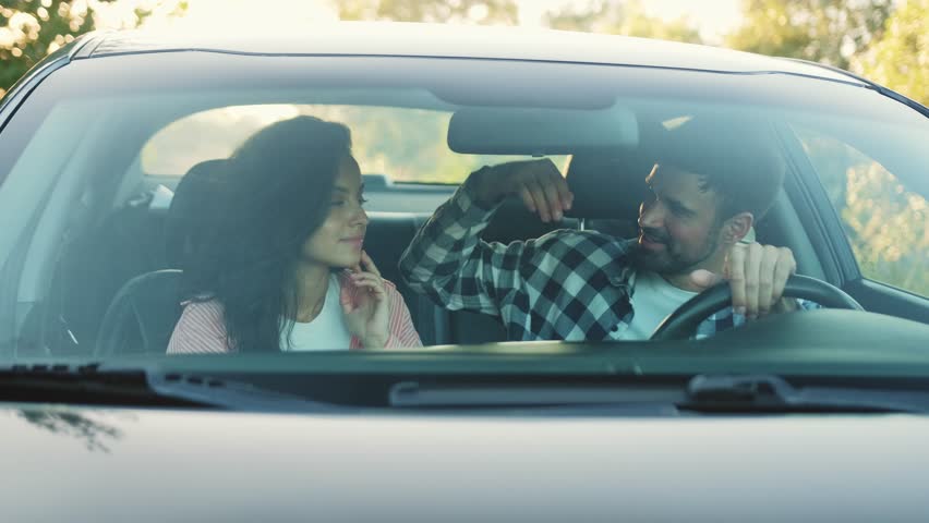Happy man hugging his girlfriend while sitting in the car. Slow motion