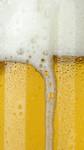 Macro shot cold beer with foam pouring in glass
