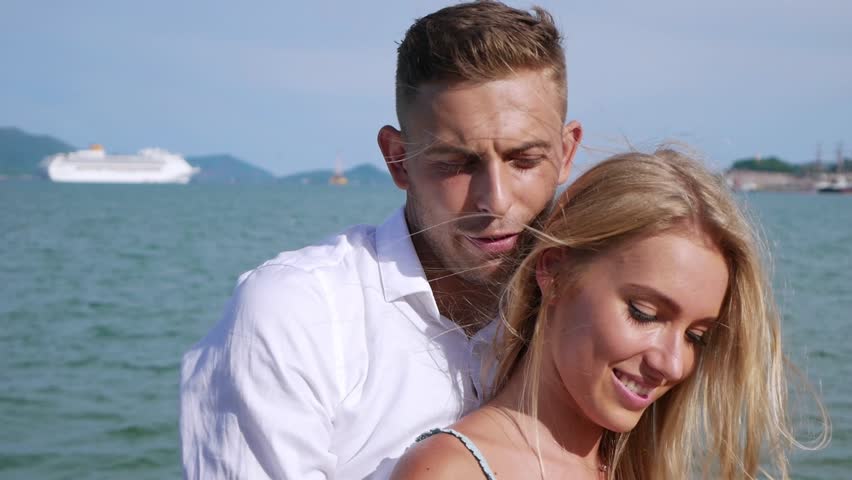 Young happy couple hugging on blue sea background. Romantic concept. HD, 1920x1080.