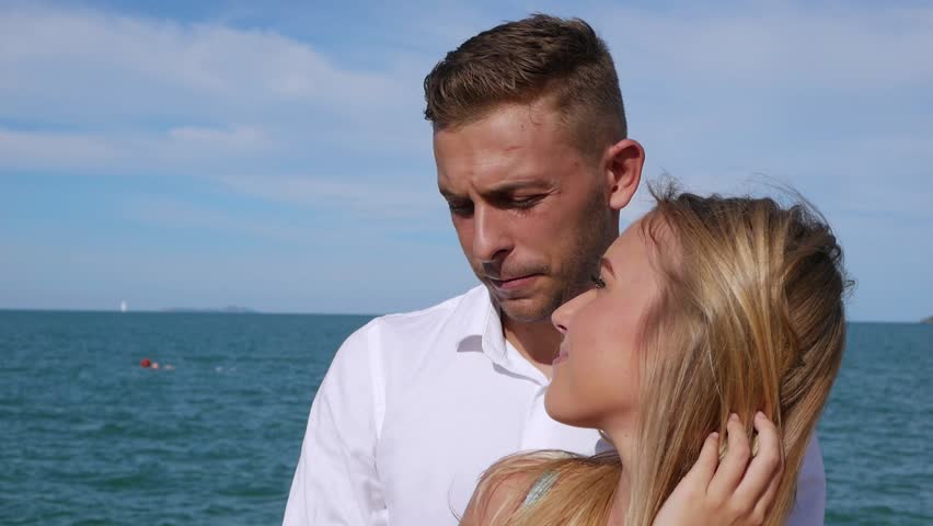 Young happy couple hugging and kissing on blue sea background. Romantic concept. HD, 1920x1080.