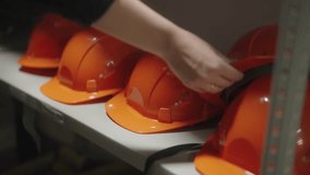 Worker selecting an orange safety helmet from a rack in warehouse. Safety helmet for factory workers in workshop and at construction.  - Powered by Shutterstock - Get 15% off with code: PIKWIZARD15
