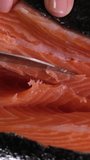 with sharp knife cut off large pieces of red fish salted salmon cooking for sushi at home slow motion video
