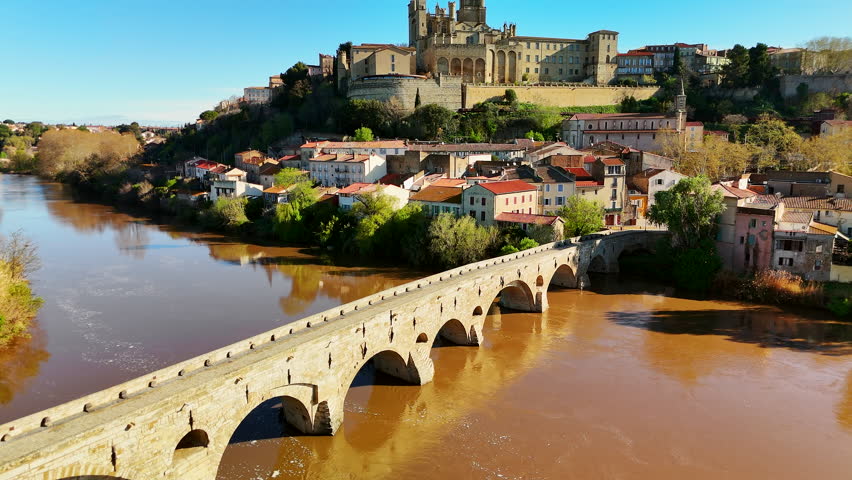 Aerial view of Beziers old town in France. The old bridge over the Orb river with the Cathedral of Saint Nazaire in Beziers, Southern France. Drone revealing footage.