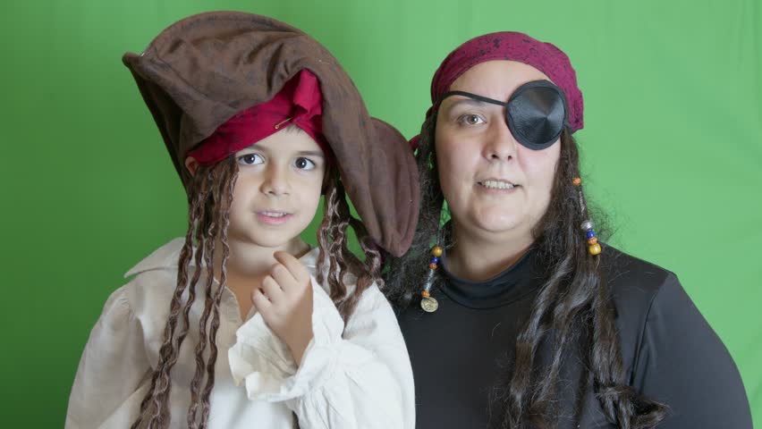 Pirate play. Mom and son dressed as pirates with cutlasses posing on the green background. slow motion. High quality 4k footage