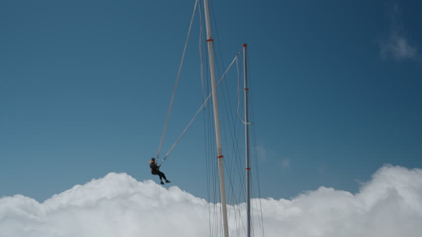 A tourist attraction a Slingshot or Catapult. high in the mountains above the clouds. The daring individual, loving thrills and adrenaline, is on the Tarzan rope and gets catapulted high into the air. Royalty-Free Stock Footage #3495593681