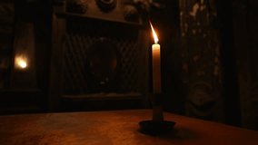 Closeup of one candle lightning in dark enigmatic room with flickering light and mystical atmosphere. Air blows out flame of burning paraffin candle in esoteric room while conducting occult ceremony. - Powered by Shutterstock - Get 15% off with code: PIKWIZARD15