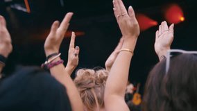 Rear view of audience clapping along with music as they watch band at outdoor summer music festival - shot in slow motion - Powered by Shutterstock - Get 15% off with code: PIKWIZARD15
