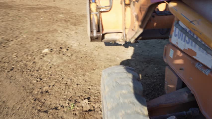 side view pov on a backhoe bulldozer contruction machine, construction site dirt road