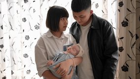 Slow-motion video of a Taiwanese mother and father in their 20s standing in front of a curtain with a 1-month-old baby girl.