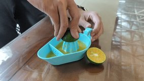 A man hand squeezing orange juice using a manual juicer, healthy drink, stock video, 4K. 