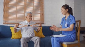 Asian senior elderly man doing physiotherapist with support from nurse. Mature older male patient sit on sofa in living room, use resistance stretch band exercise with caregiver at home nursing care. - Powered by Shutterstock - Get 15% off with code: PIKWIZARD15