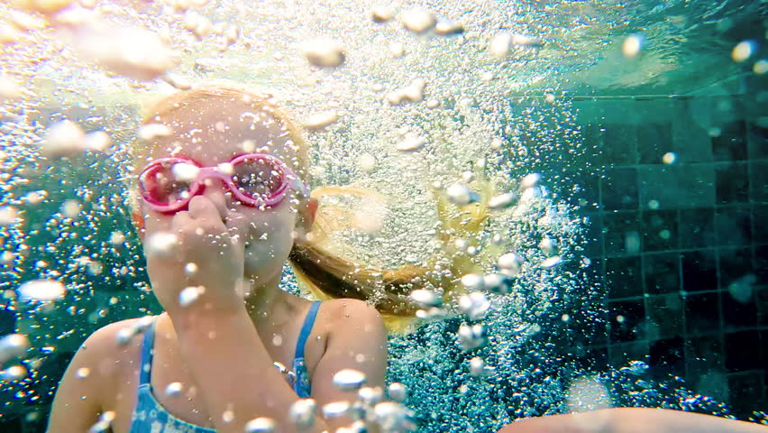 Cute girl swim in the swimming pool. Happy smiling girl diving and swimming. Girl diving underwater in pool. 