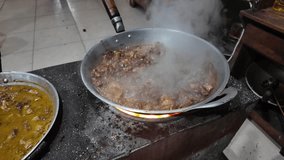 4k video footage of Javanese man cooking traditional goat meat using a wok pan on charcoal with blazing fire and smoke rising from the stove. Tongseng and Sate klathak from Imogiri, Yogyakarta