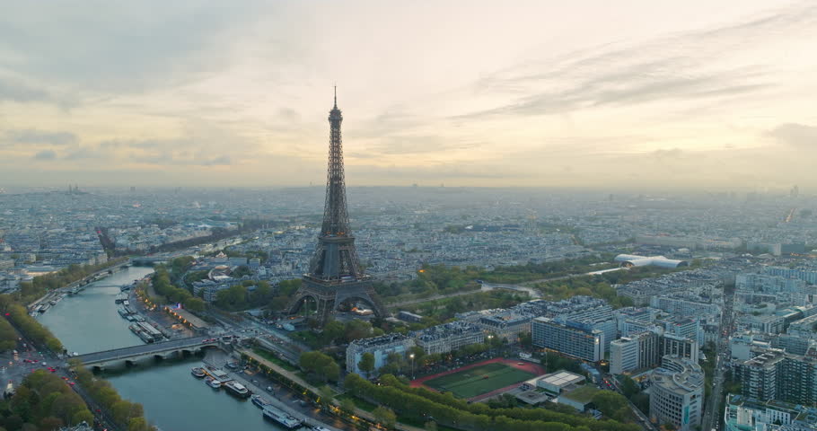 Beautiful view of famous Eiffel Tower in France with magical morning cloud and fog. Wide establishing aerial drone fly over seine river in paris city center, best travel destination landmark in Europe