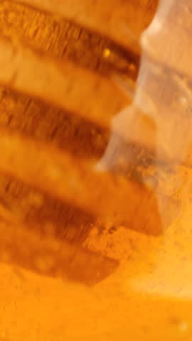 Taking a spoon out of honey. Thick organic honey dripping from a wooden honey spoon