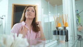 Mirror image of Attractive Young Woman Brushing Her Thick Beautiful Hair With Comb While Standing Near Mirror In Bathroom, Looking To Her Reflection. Hair care Concept. - Powered by Shutterstock - Get 15% off with code: PIKWIZARD15