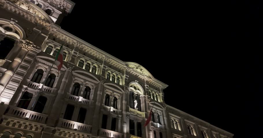 A slow pan shot of Comune di Trieste Piazza Grande Trieste Italy at night revealing the majestic facade with lights in 4K
