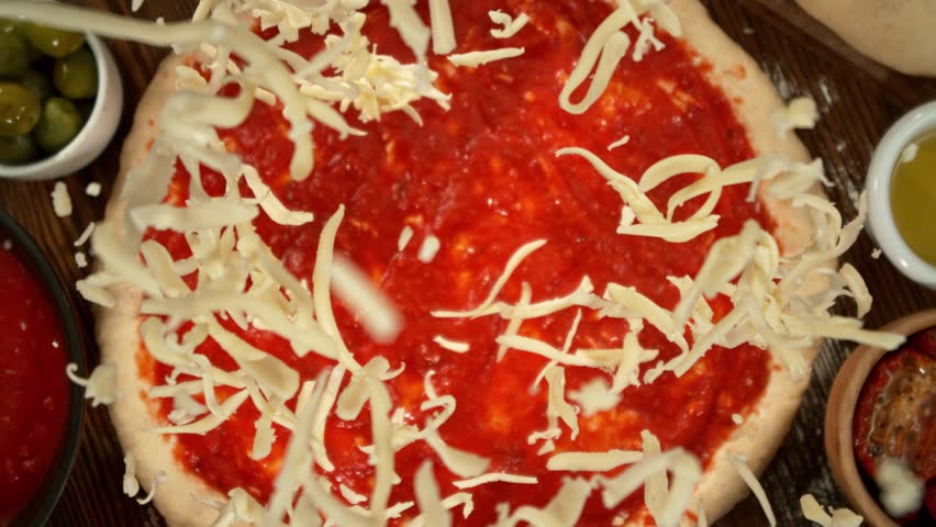 Super slow motion of falling grated cheese on pizza dough with camera follow and rotation. Filmed on high speed cinema camera, 1000 fps.