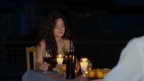 Happy pretty lady holding glass of wine while talking with her boyfriend on terrace on the date. Romantic date on the roof. Romantic concept. Couple in love. Real time - Powered by Shutterstock - Get 15% off with code: PIKWIZARD15