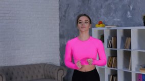 Fit young woman in sportswear running on spot at home while doing cardio workout training, using camera on tripod to making video for vlog. Fitness and healthy lifestyle concept. Real time video.