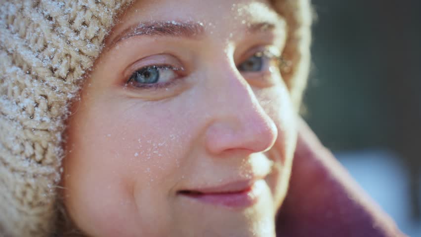 Close-up of woman open her eyes with snow on big eyelashes.