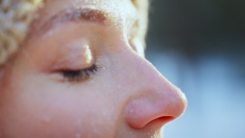 Close-up of woman open her eyes with snow on big eyelashes.