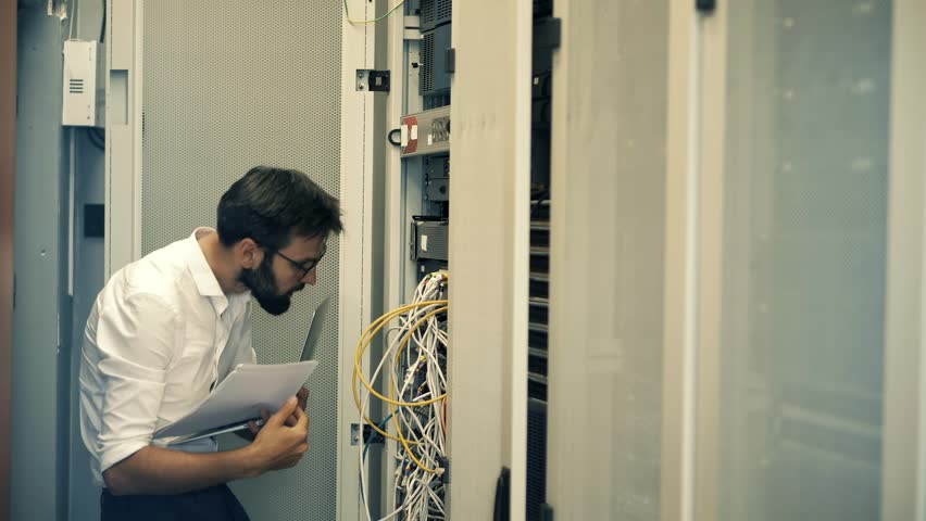 System Engineer Control Room IT Administrator. Server Engineer Work On Laptop in Data Center. Male Server IT Engineer Work Data Center. Man Work In Server Room. Male Typing On Laptop In Server Room Royalty-Free Stock Footage #3496296215