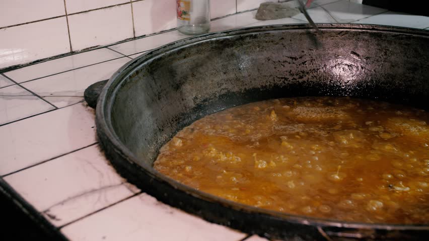 Cooking delicious pilaf in a large cauldron
