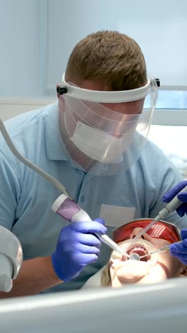 professional teeth cleaning in a dental clinic, removing stones and plaque, young specialists working with a woman, cleaning a saliva ejector, sucking out saliva, applying paint to the teeth Royalty-Free Stock Footage #3496352347
