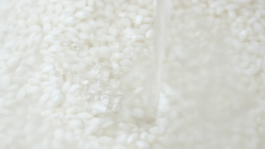 Pouring water in bowl with raw rice