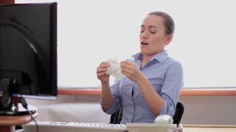Sick business woman with flu blowing nose in tissue
