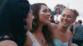 Three female friends arm in arm wearing glitter singing and dancing watching band at outdoor summer music festival - shot in slow motion - Powered by Shutterstock - Get 15% off with code: PIKWIZARD15