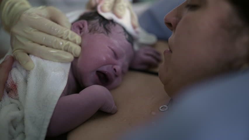 Newborn baby crying for the first time right after birth resting on mother's chest, mother and infant's first seconds of life together, maternal care concept bringing a human being to life