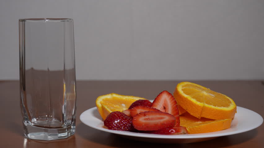 The wine is poured into a glass. Chopped strawberries and oranges.