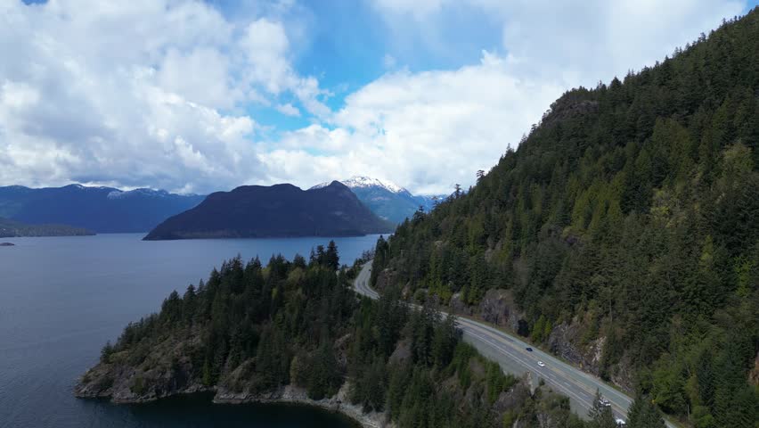 Scenic Highway on the Coast near Squamish, Howe Sound. Trees, Mountain. Blue Sky and Clouds, Springtime. British Columbia, Canada. Royalty-Free Stock Footage #3496529703
