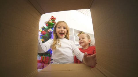 The happy kids open the box near the christmas tree
