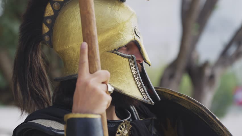 Spartan hoplite warrior posing holding attack spear and protecting with shield at Acropolis in Athens, Greece, cinematic slow motion shot