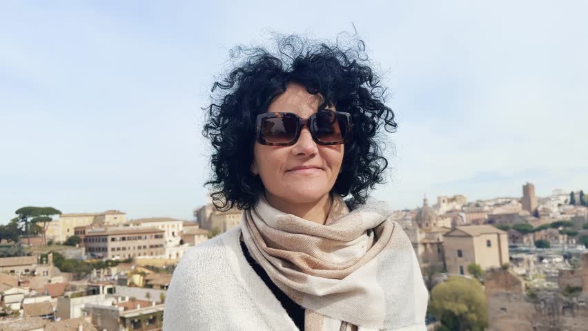 Curly hair woman with glasses visiting Roman Forum on sightseeing tour in Rome, Italy