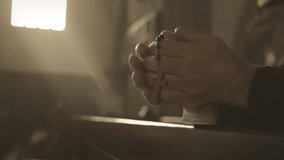 Man hands holding rosary with cross while praying in church close up. Prayer beads in male caucasian monk clasped arms closeup. Worship concept - Powered by Shutterstock - Get 15% off with code: PIKWIZARD15