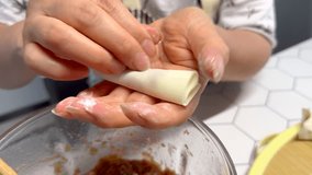Close up view of woman hand holding Chinese Wonton and Dumpling with filling ground meat, fresh shiitake mushrooms, stemmed and minced. Real time handheld video 4K
