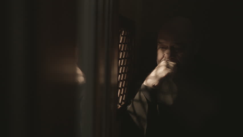 Christian monk in dark confessional booth, crossing and talking medium shot. Monastery clergyman listening to confession through window. Forgiveness concept