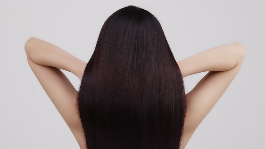 Slow motion rear view of young Asian girl shakes long straight hair. Female model is fluttering hair.
