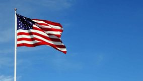 Beautiful Real American flag waving in the wind, in slow motion, with vibrant red white and blue colors lit by the sun, against blue sky for copy space. - Powered by Shutterstock - Get 15% off with code: PIKWIZARD15